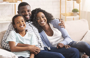 About Lovett Dental Beaumont, family of three sitting on couch smiling