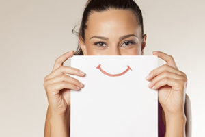 Teeth Cleaning Beaumont TX, woman holding paper over mouth with smile on it