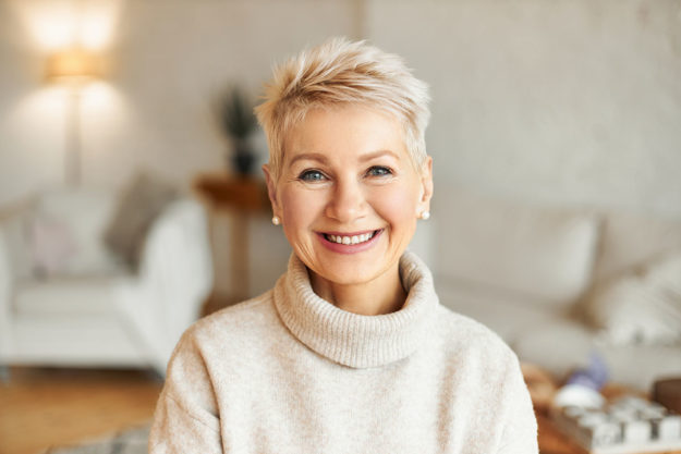 how do dental implants compare to real teeth_ older woman smiling after learning how do dental implants compare to real teeth