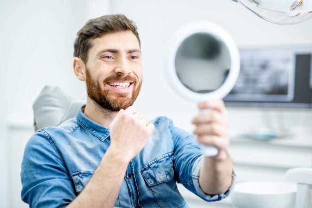 teeth-replacement man looking at his teeth replacement