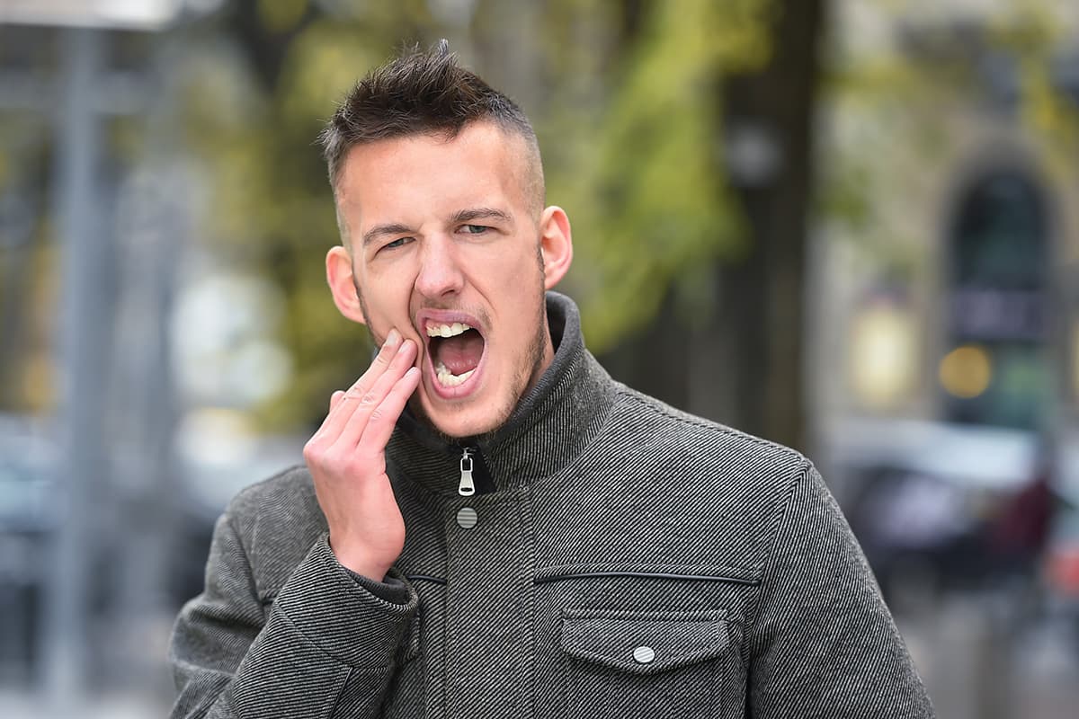 tooth pain in cold weather man holding jaw experiencing tooth pain in cold weather