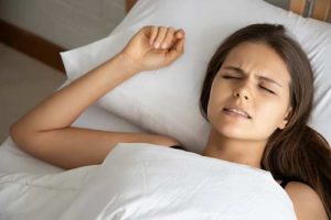 woman in bed dealing with teeth grinding